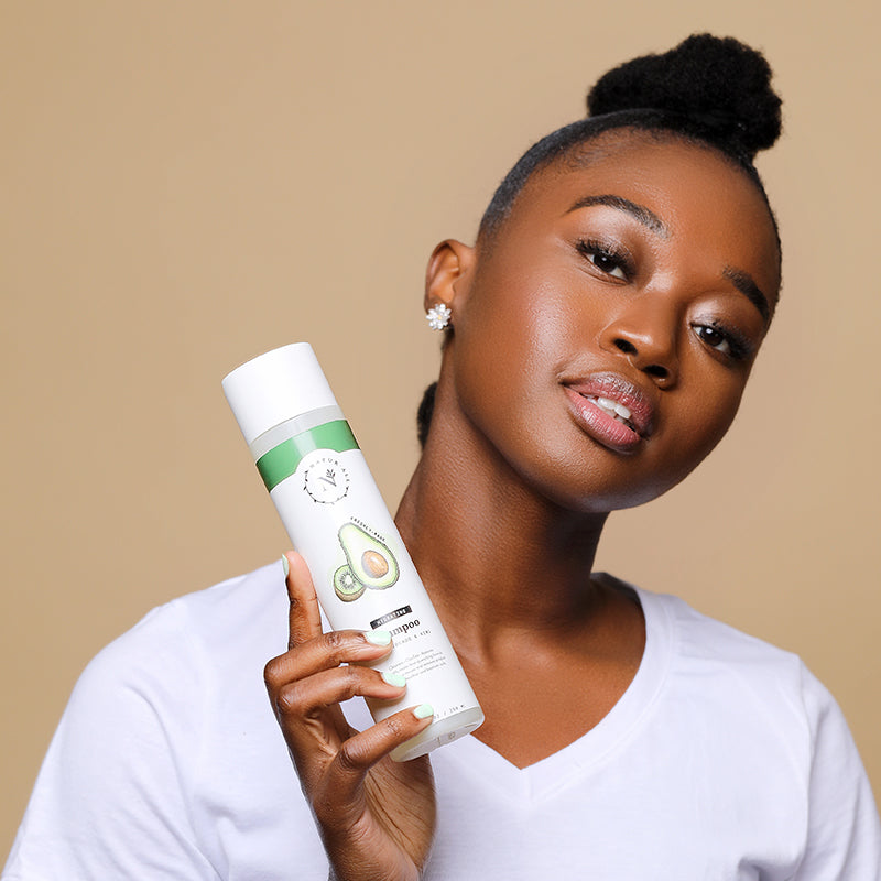 A woman with a high puff holding NaturAll Hydrating Shampoo